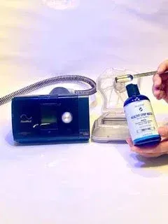 Hand holding a SilverPAP bottle beside a CPAP machine with its water chamber lifted open